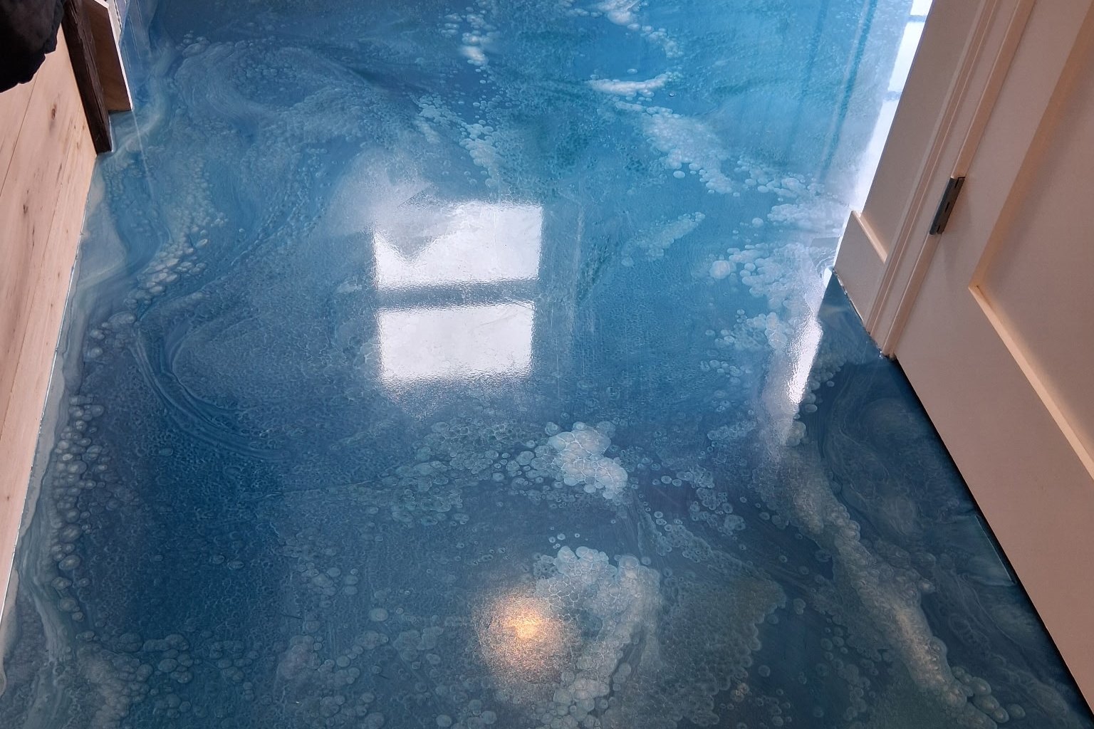 Blue metallic resin floor reflecting a doorway